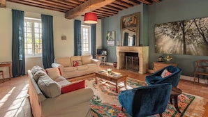 A cozy living room with a sofa, armchair, fireplace, and a large painting. - Beautiful 1900 Demeure with swimming pool and enclosed garden, in a charming village (Apremont-sur-Allier)