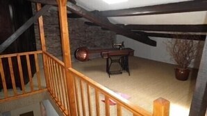 Een kamer met zichtbare houten balken, een naaimachine en een potplant.