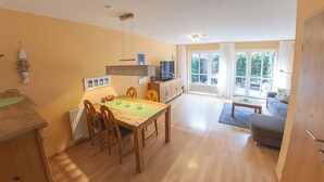A spacious living area with a wooden dining table, a sofa, and a TV.