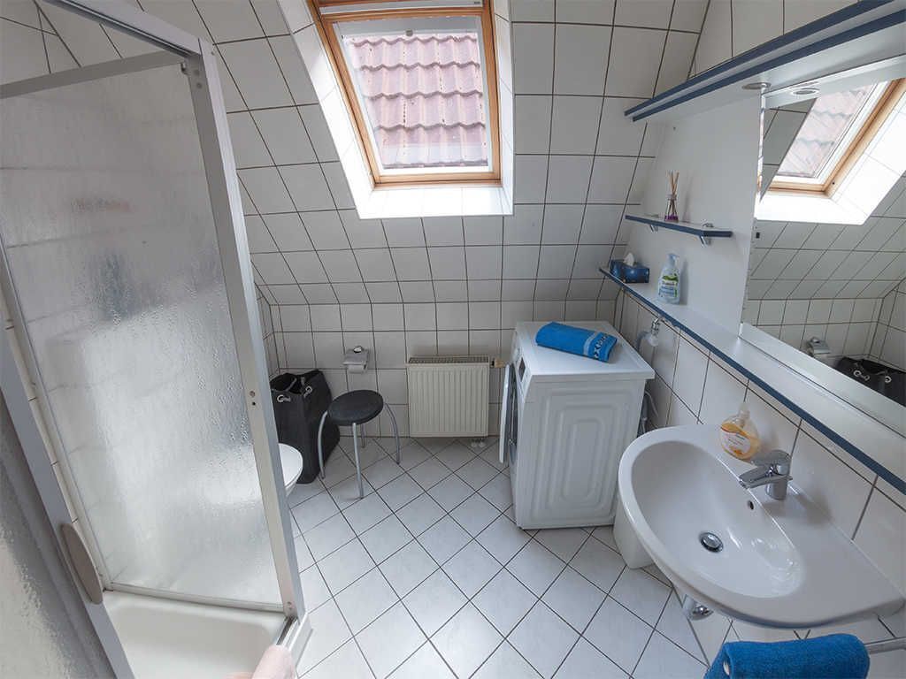 A bathroom with a shower, a toilet, a sink, and a small window.