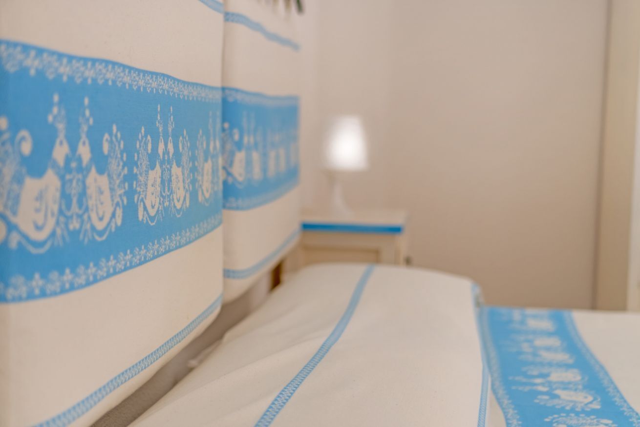 A bed with a blue and white patterned bedspread and a matching blue headboard.