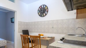 Cocina compacta con comedor, un reloj en la pared y un lavamanos.