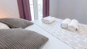 Una habitación de hotel con una cama, dos almohadas y dos toallas enrolladas.