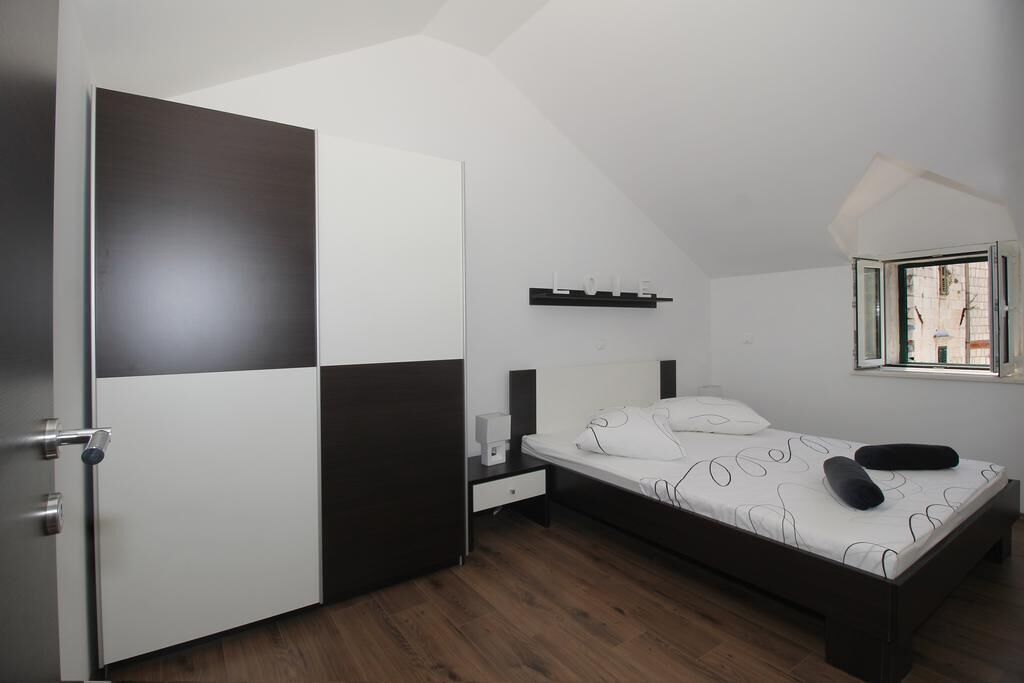 Ein Schlafzimmer mit Bett, Nachttisch, Ablagefläche an der Wand und einem Fenster.