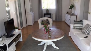A modern living room with a round wooden coffee table, white sofas, and a television on a white stand. - Santa Belgica, Altea (Altea)