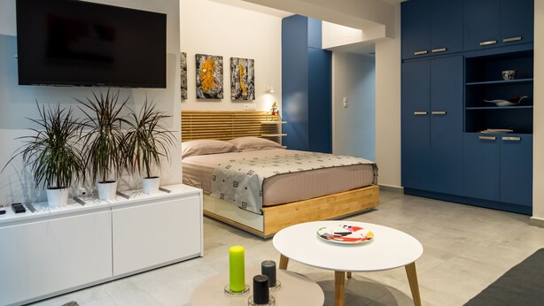 Une chambre à coucher moderne avec un lit, une table de chevet et un téléviseur fixé au mur.