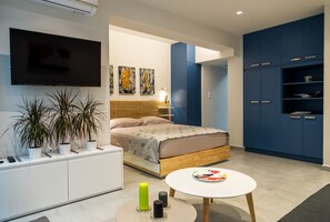 Une chambre à coucher moderne avec un lit, une table de chevet et un téléviseur fixé au mur.
