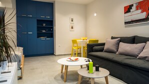 Un salon moderne avec un canapé gris, une petite table ronde ornée de bougies, un meuble bleu et une table à manger jaune avec des chaises.