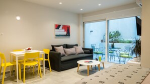 Un salon moderne comprenant un canapé, une table à manger et des chaises, une petite table basse et une porte-fenêtre coulissante donnant sur une terrasse extérieure.