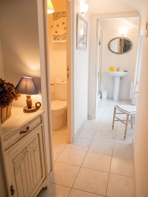 A narrow hallway leading to a bathroom with a toilet, sink, and mirror. - Homerez - House in Cléden-Cap-Sizun (Cléden-Cap-Sizun)