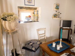A room with a wooden table, a chair, a blue tray with cups, a television, and a window with a view of the sea. - Homerez - House in Cléden-Cap-Sizun (Cléden-Cap-Sizun)