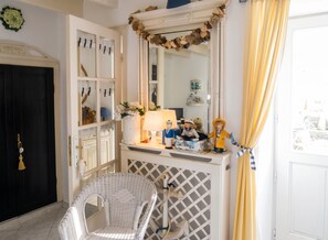 A room with a white console table, a wicker chair, a mirror, and a door with a black frame.