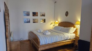 A neatly made bed with white linens and towels, a wooden headboard, and a nightstand with a lamp. There are three framed pictures on the wall above the bed. - Bright apartment in the Center of Rome 70 sqm wifi near Piazza di spagna (Roma)