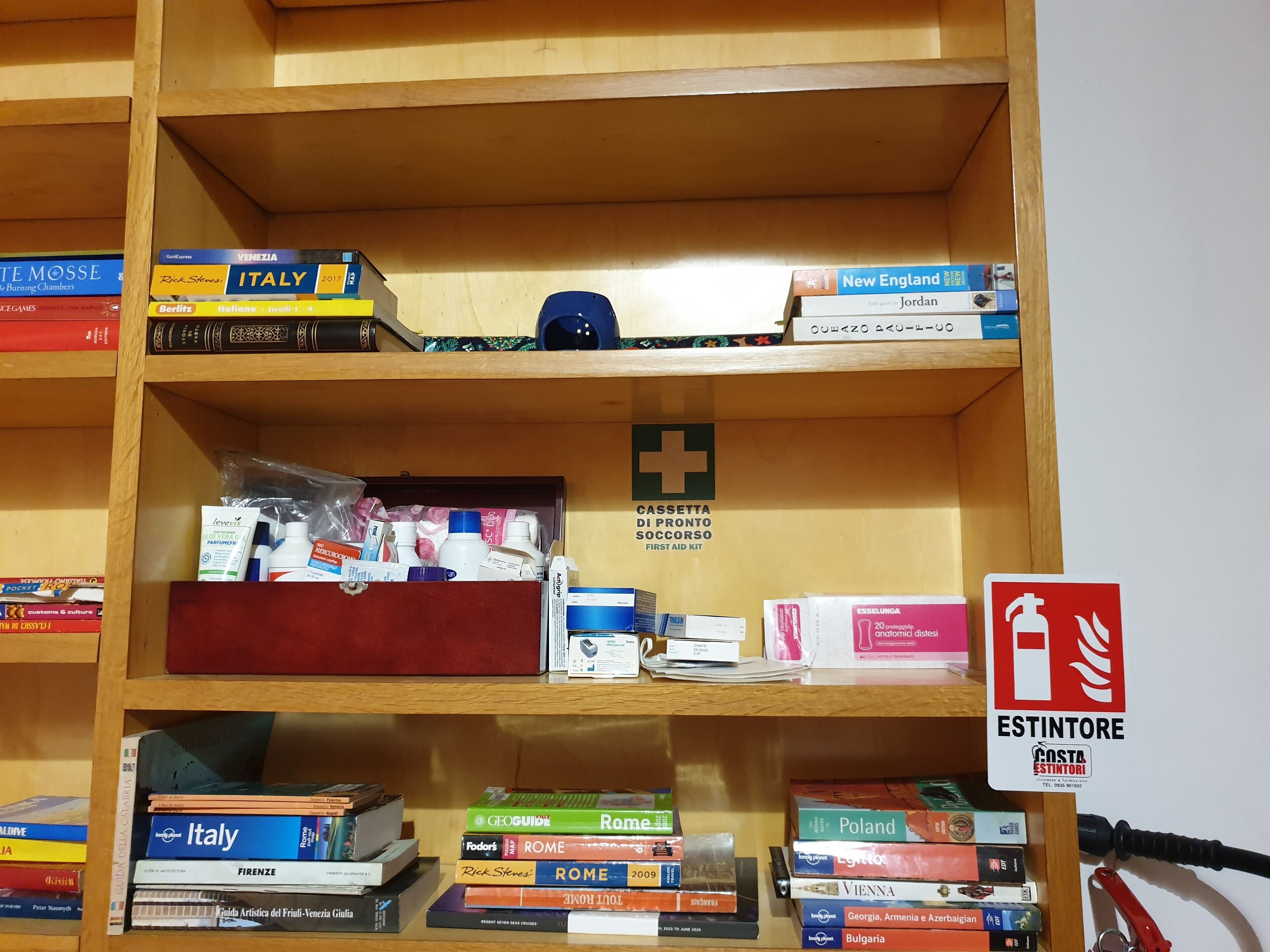A bookshelf with travel guides and a first aid kit.