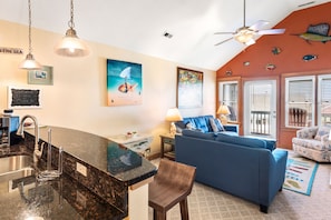 A kitchen with a granite countertop, a sink, and a dining area with a blue sofa and a small table.