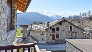 A stone building with a wooden balcony overlooking a mountainous landscape. - Maison Chez Nous by Interhome (Sarre)