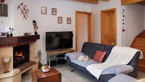 Una sala acogedora con chimenea, un sofá, un televisor y un cofre de madera.