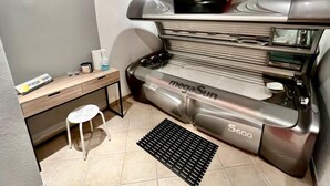 Cocina compacta con microondas integrado, una mesita de madera, un taburete y una campana extractora.