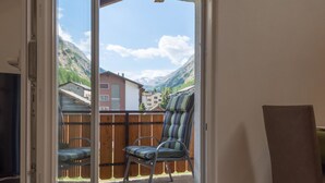 A room with a sliding glass door leading to a balcony with a view of mountains and houses. - Haus Bergsonne by Interhome (Saas-Almagell)