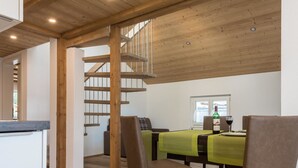 A dining area with a wooden staircase, a table with a green tablecloth, and leather chairs. - Haus Bergsonne by Interhome (Saas-Almagell)
