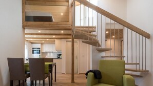A modern interior with a wooden staircase, a dining area with chairs and a table, and a green armchair. - Haus Bergsonne by Interhome (Saas-Almagell)