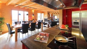 Une cuisine moderne dotée d’un îlot central, d’appareils électroménagers en acier inoxydable et d’un plafond en bois.