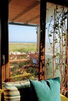 Habitación con vista al mar, techo de madera y ventana que ofrece vistas al mar y al follaje exterior.