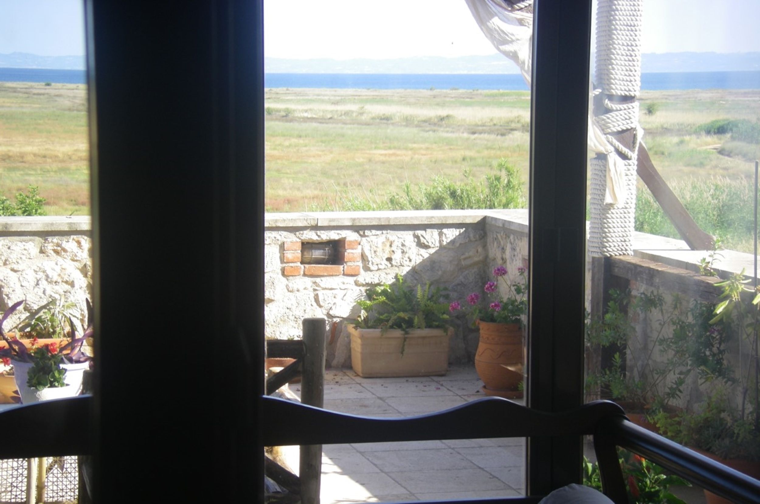 A balcony with a view of a grassy field and mountains in the distance.