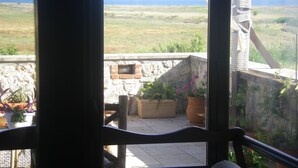 A balcony with a view of a grassy field and mountains in the distance.