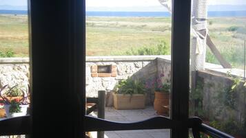 A balcony with a view of a grassy field and mountains in the distance.