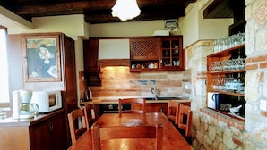 A rustic kitchen with wooden cabinets, a dining table, and a stone wall.