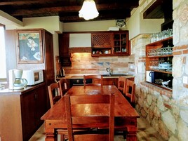 Una cocina rústica con armarios de madera, una mesa de comedor y una pared de piedra.
