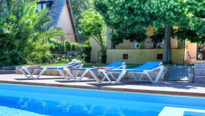 A swimming pool with clear blue water, surrounded by lounge chairs and greenery. - La Tilia II by Interhome (Calonge)