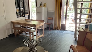 A modern living room with a dining area, a large window with curtains, and a view of the outdoors.