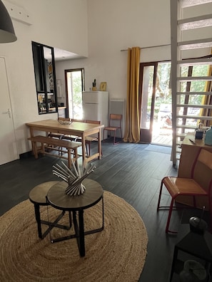 Uma sala de estar moderna com área de jantar, uma janela grande com cortinas e vista para o exterior.