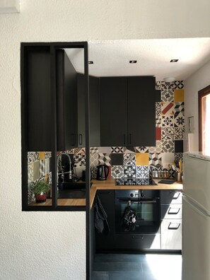 Cozinha compacta com armários escuros, cafeteira e micro-ondas.