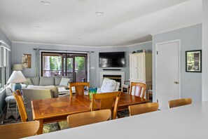 Un coin repas avec une table et des chaises en bois, un canapé, un téléviseur et une cheminée.