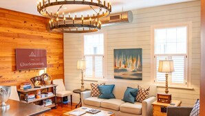 A cozy living room with a wooden ceiling, a chandelier, a sofa set, a coffee table, and a bookshelf. - Luxurious Mansion Downtown Charleston (Charleston)