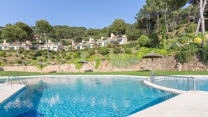 Une piscine bordée d’un mur en pierre, offrant une vue sur une colline parsemée d’arbres et de bâtiments.