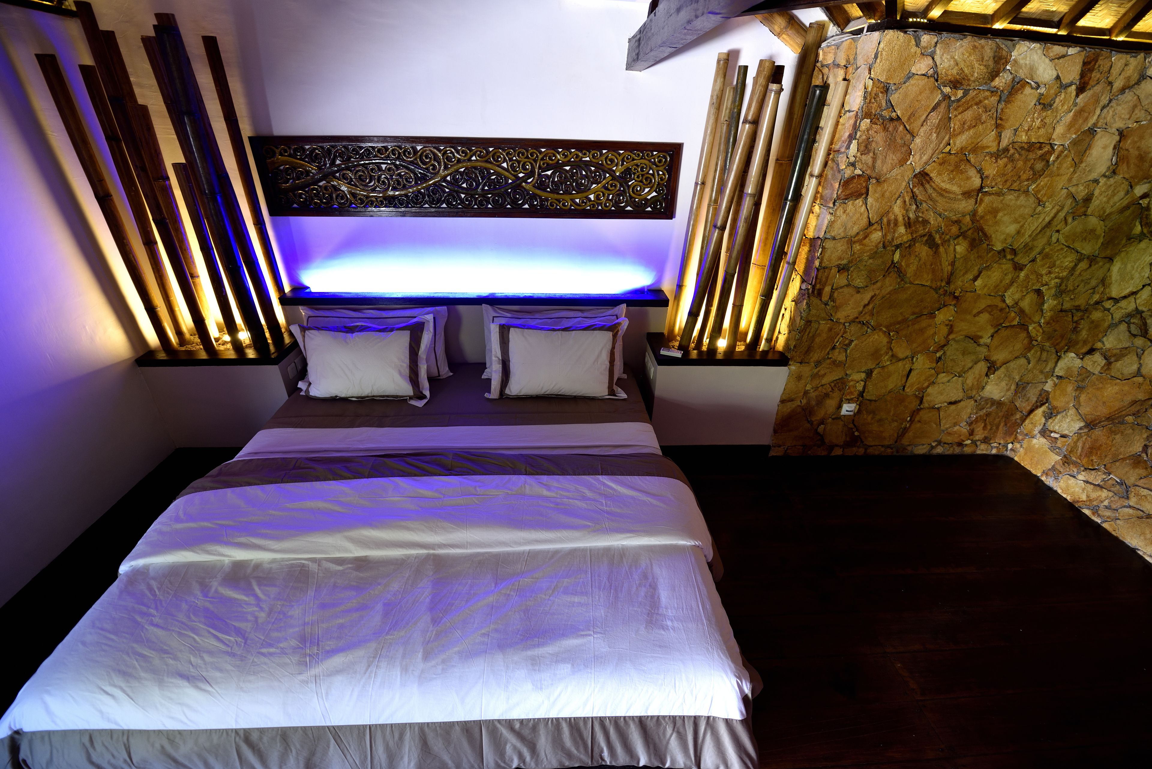 Un dormitorio moderno con una cama grande, un adorno de pared y una pared de piedra decorativa.