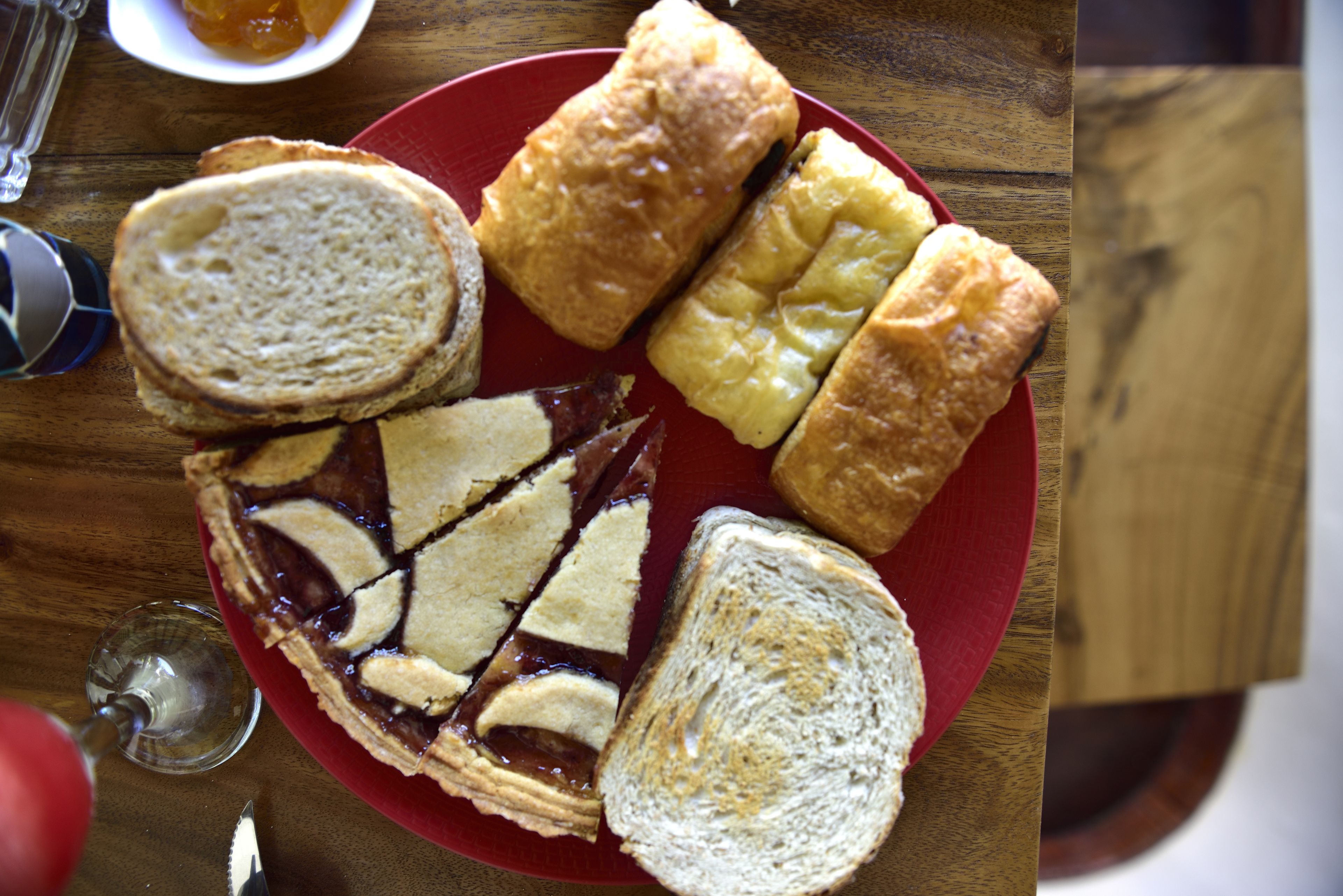 A plate with various types of bread and a slice of pie on a wooden table.