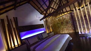 Une chambre avec un lit, un mur en pierre et une structure de plafond en bois.