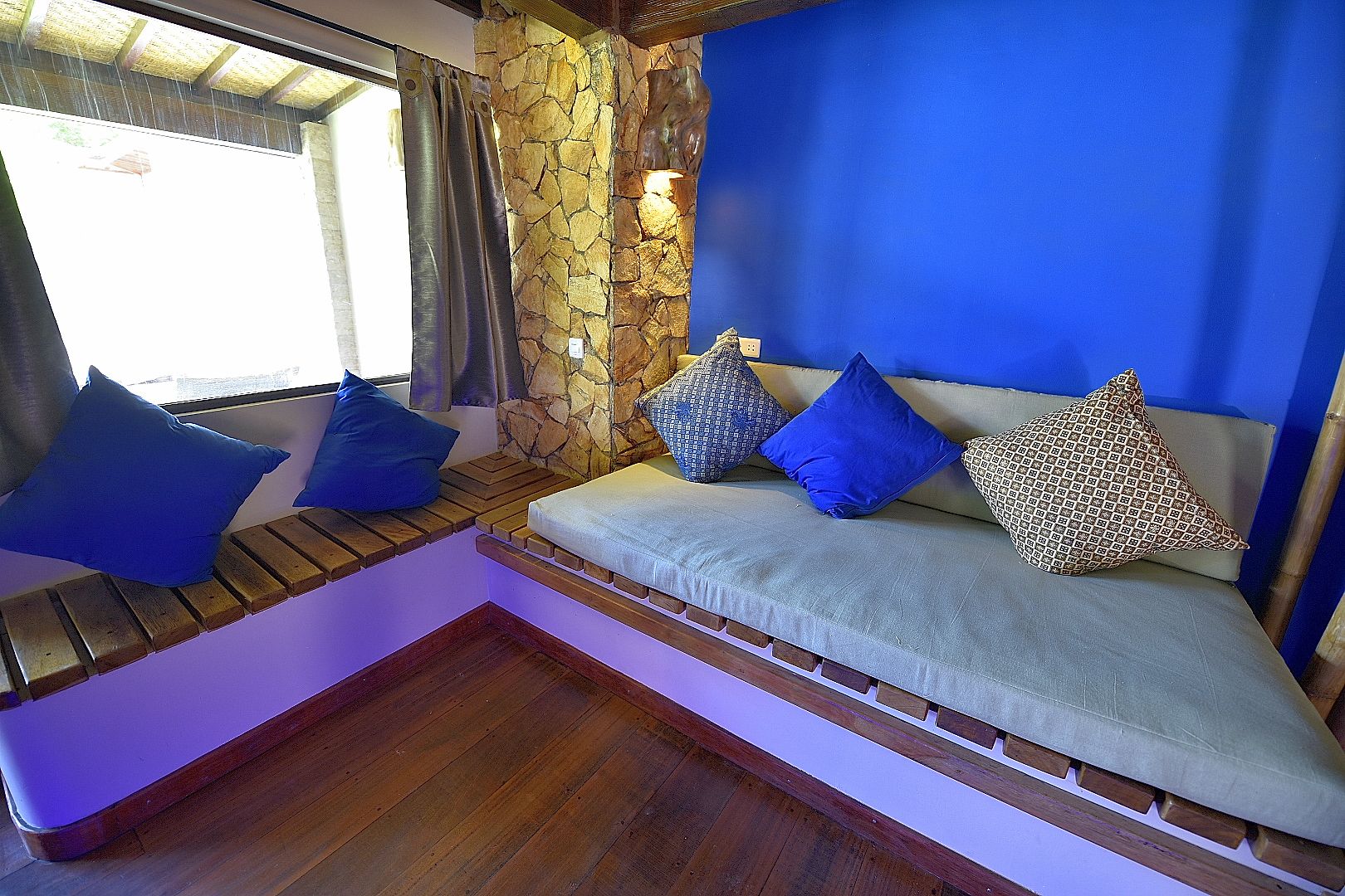 Ein gemütlicher Sitzbereich mit einer Steinwand, einer blauen Wand und Holzbanken.