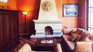 A cozy living room with a fireplace, wooden furniture, and a painting on the wall.