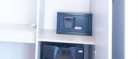 A storage closet with a small safe, hooks for hanging items, and a door leading to a hallway.