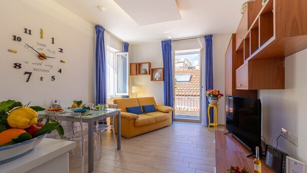 Una sala moderna con sofá, mesa de comedor y televisor.