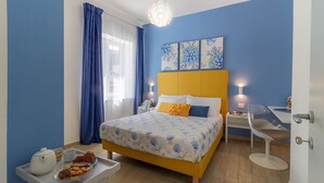 Un dormitorio con una cama, mesitas de noche, una silla y una bandeja con cosas para el desayuno.