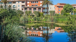 Ein Hotel mit mehreren Etagen, Balkonen und Spiegelung in einem Teich.