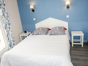 A bed with white bedding, two nightstands, and a blue wall.