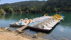 Une rangée de pédalos était amarrée à un quai au bord du lac, avec une colline boisée en arrière-plan.